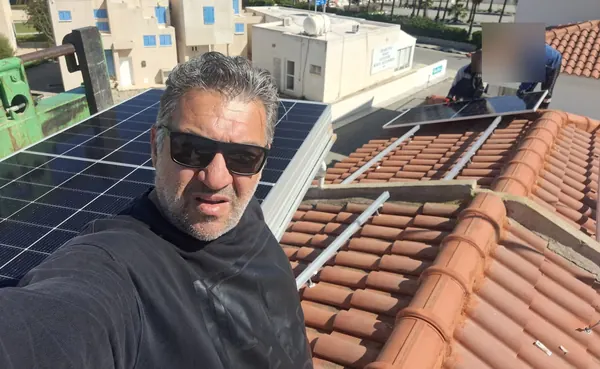 Ο ιδιοκτήτης της Treecom Energy σε κεραμοσκεπή καθώς τοποθετούνται τα πάνελ